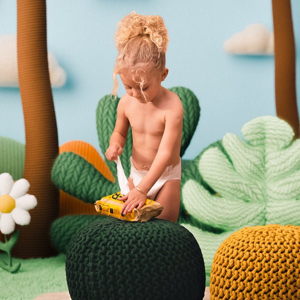 Child playing with a toy in a knitted forest setting