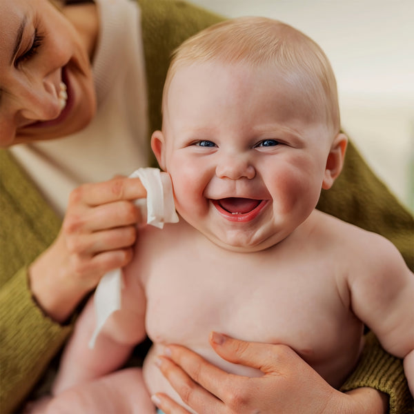 Baby laughing while being held by a smiling adult