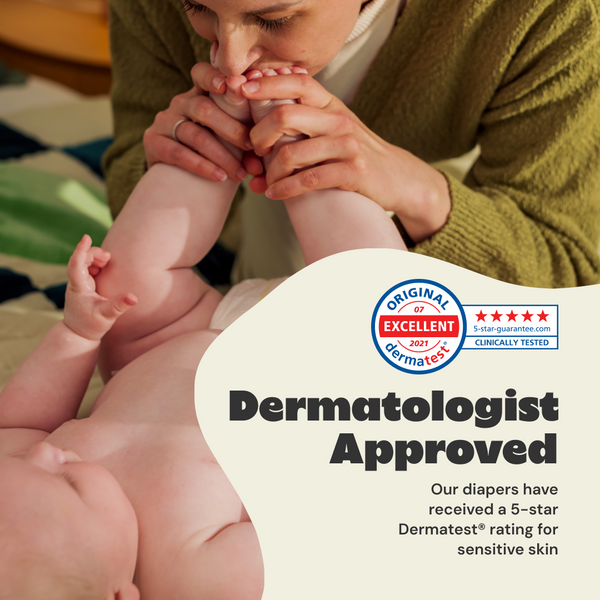 Person holding baby's feet with Dermatologist Approved label on diaper