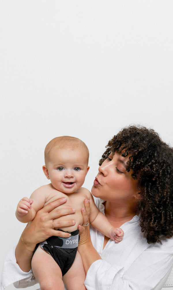 Woman holding a baby wearing a black diaper with a white background