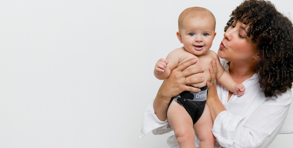 Woman holding a baby wearing a diaper with a visible brand logo on a white background