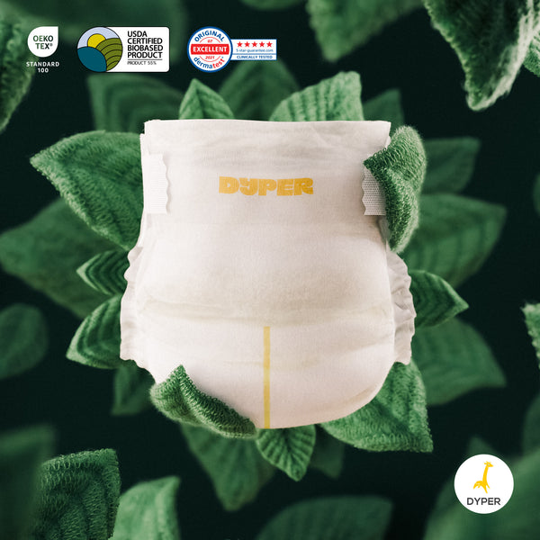 White diaper with green trim on a leafy green background, featuring Dyper branding and certification logos.