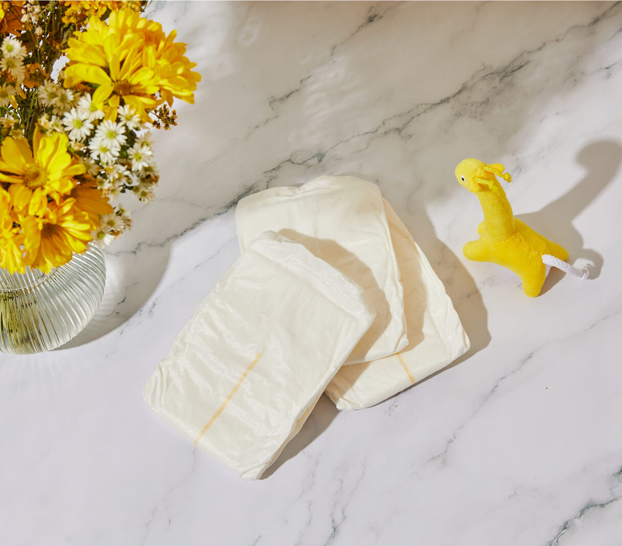 Dyper diapers on a marble surface next to flowers