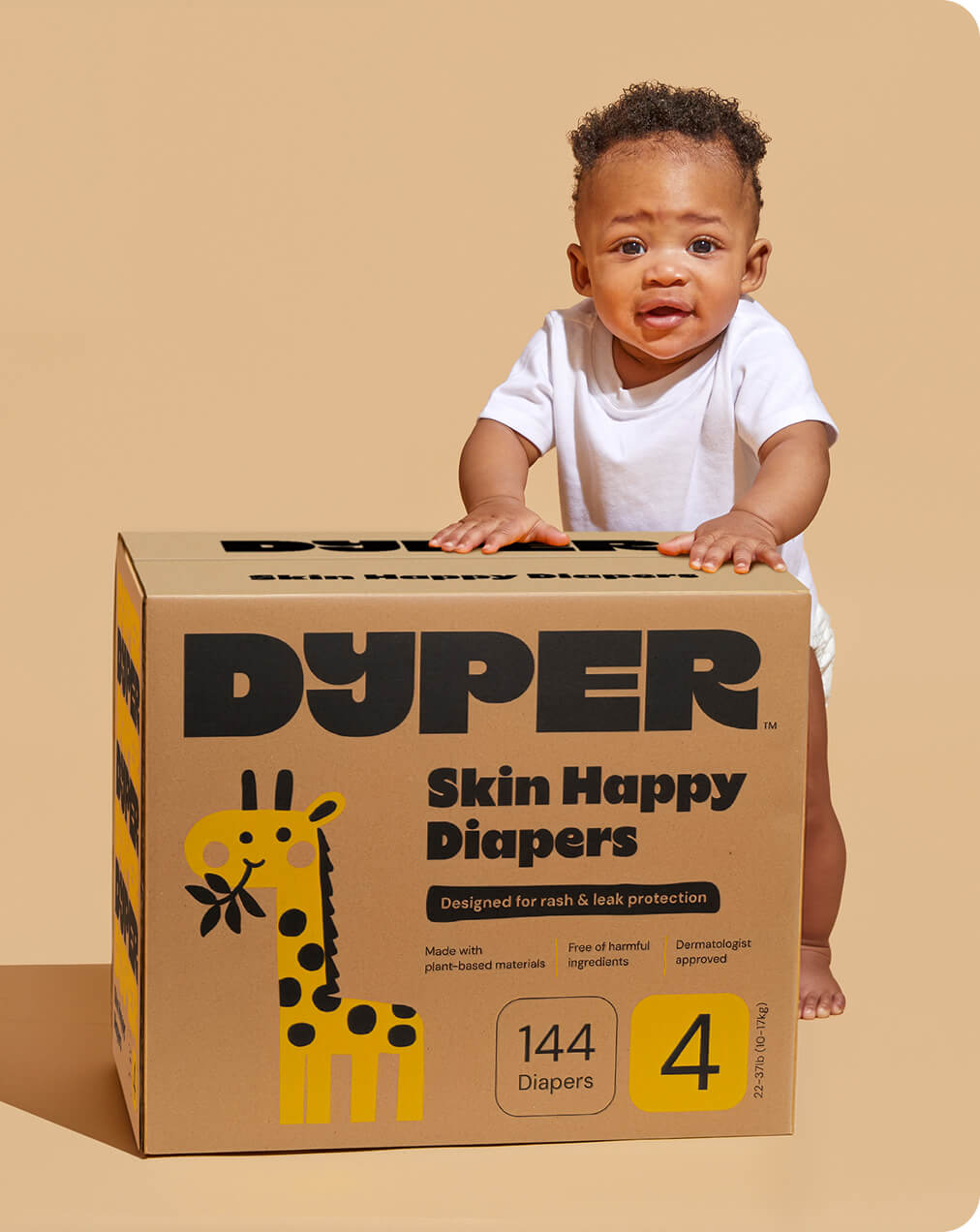 A baby with a box of Dyper Skin Happy Diapers